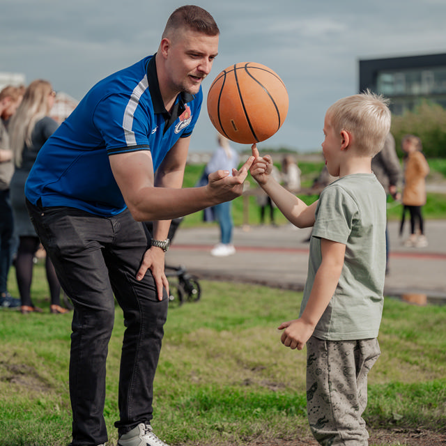Mike Nielsen sammen med dreng til event. De prøver at spinne en basketball på drengens finger